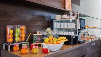 Una colazione a buffet con frutta, condimenti e una macchina per il caffè.