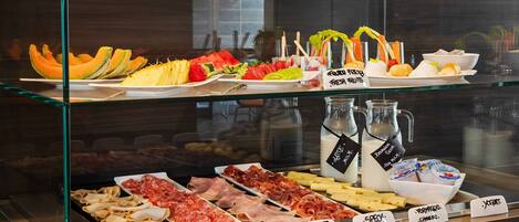 A deli counter with various meats and cheeses, including turkey, salami, ham, and prosciutto.