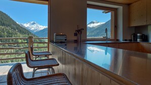 Eine Küche mit einer großen Kochinsel, Holzschränken und Blick auf schneebedeckte Berge.