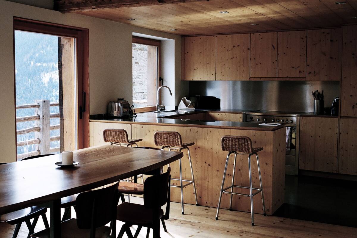 A kitchen with wooden cabinets, a stainless steel sink, and a wooden dining table with four chairs.