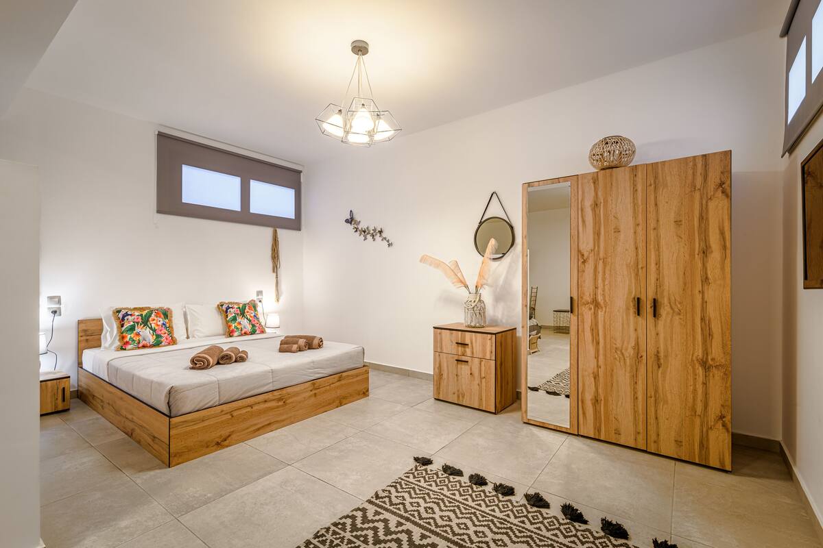 A bedroom with a wooden bed, a large mirror, and a wardrobe.