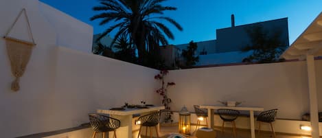 An outdoor patio with a white table and chairs, a hanging basket, and a lantern.