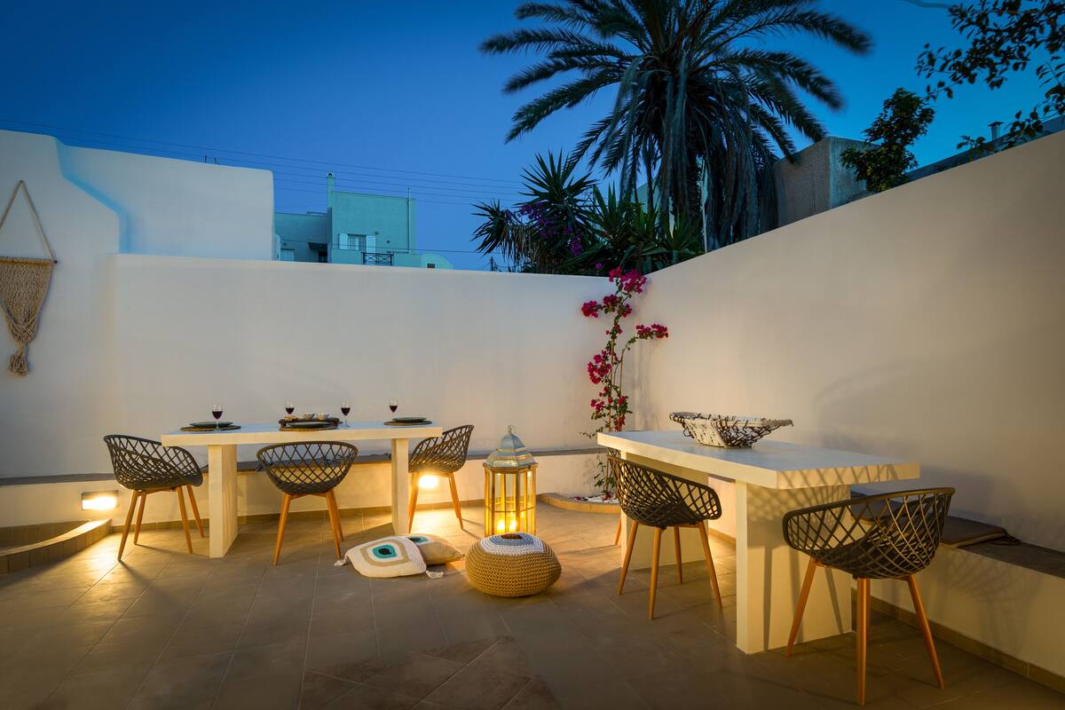 An outdoor dining area with a table and chairs, a lantern, and a decorative plant.