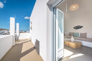 Een balkon met een bank en een salontafel, een schuifdeur en uitzicht op de stad.