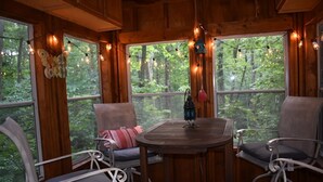 A cozy cabin interior with wooden walls, large windows, and string lights.