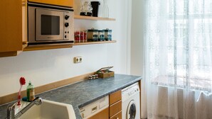 A compact kitchen with a microwave, sink, and washing machine. - Apartment Annabelle (Vienna)