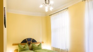 A bedroom with a bed, a nightstand, a lamp, a ceiling light, and a window with curtains. - Apartment Annabelle (Vienna)