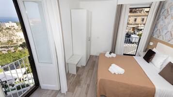 Une chambre d’hôtel comprenant un lit, un petit coin salon, une armoire et un balcon avec vue sur la ville.