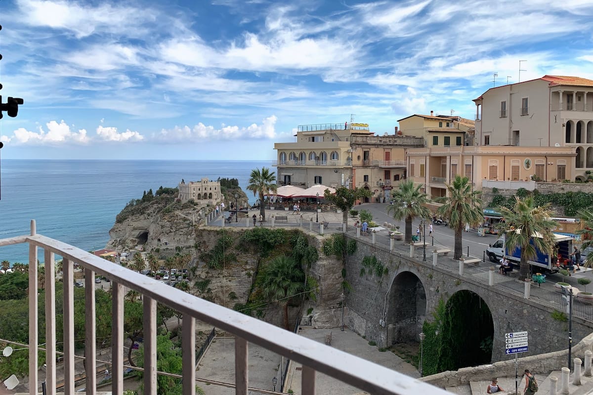 Un pueblo costero con edificios históricos, un puente y vista al mar.