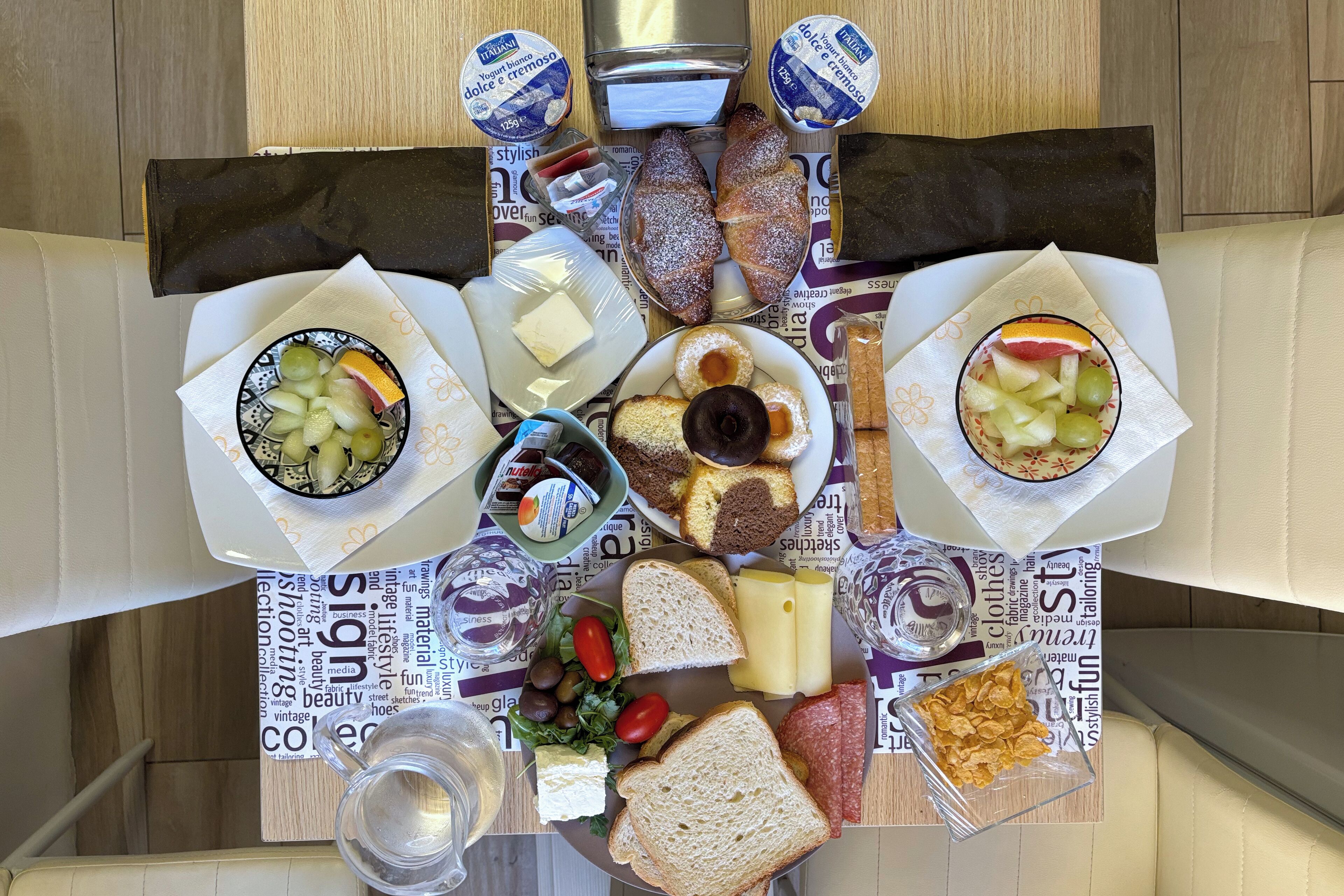 Una mesa dispuesta con diversos alimentos, incluyendo pan, queso, frutas y una botella de agua.