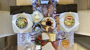 Una mesa dispuesta con diversos alimentos, incluyendo pan, queso, frutas y una botella de agua.