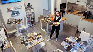 Una cocina moderna con armarios blancos, encimera de madera y una zona de comedor con sillas blancas.