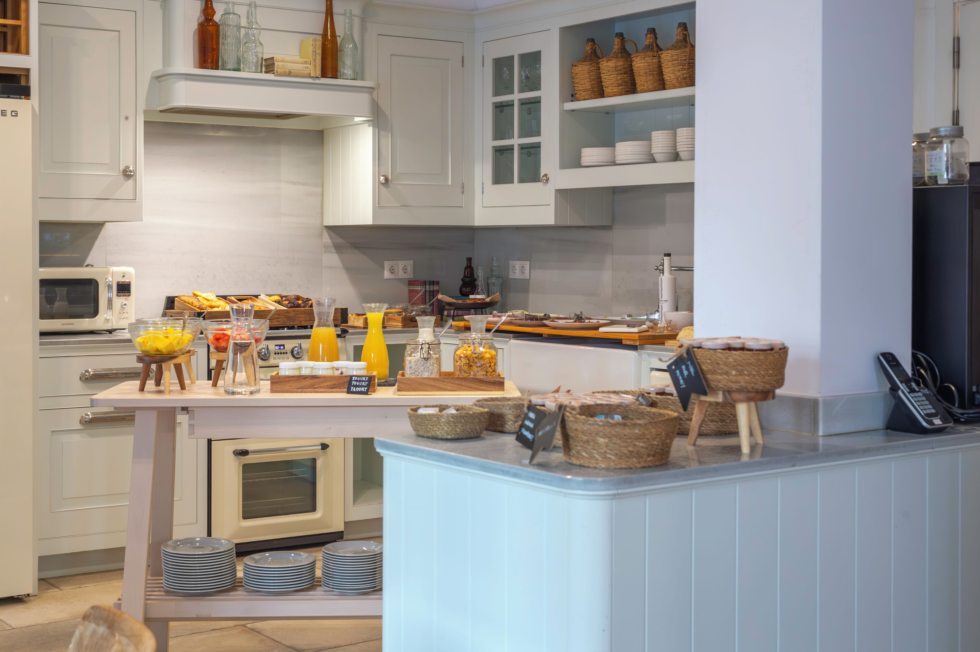 A modern kitchen with white cabinetry, a built-in oven, and a breakfast bar with various food items and condiments.
