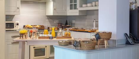 A modern kitchen with white cabinetry, a built-in oven, and a breakfast bar with various food items and condiments.