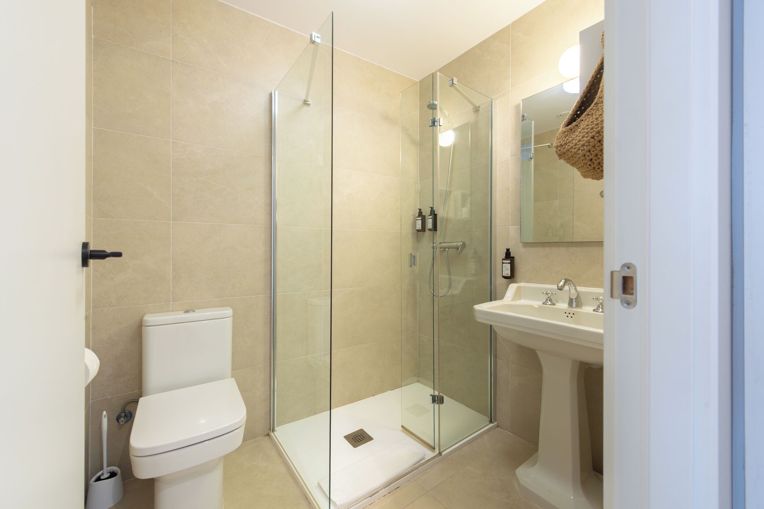 A modern bathroom with a glass-enclosed shower, a white sink, and a toilet.