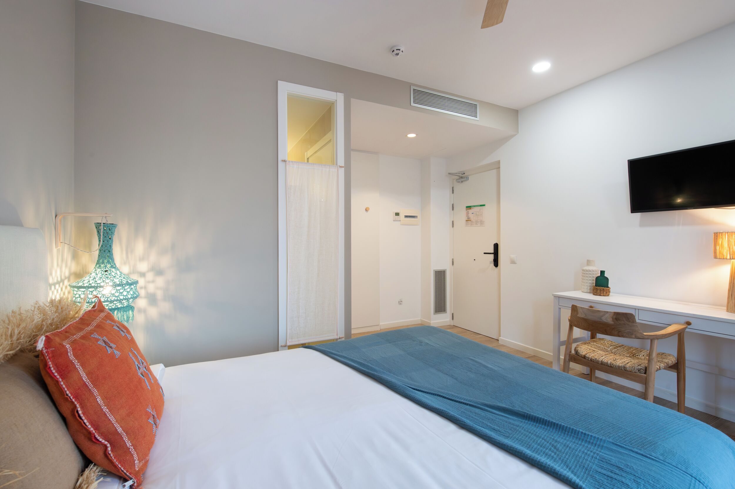 Une chambre à coucher avec un lit, un bureau, une chaise et un téléviseur fixé au mur.