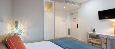 Une chambre à coucher avec un lit, un bureau, une chaise et un téléviseur fixé au mur.