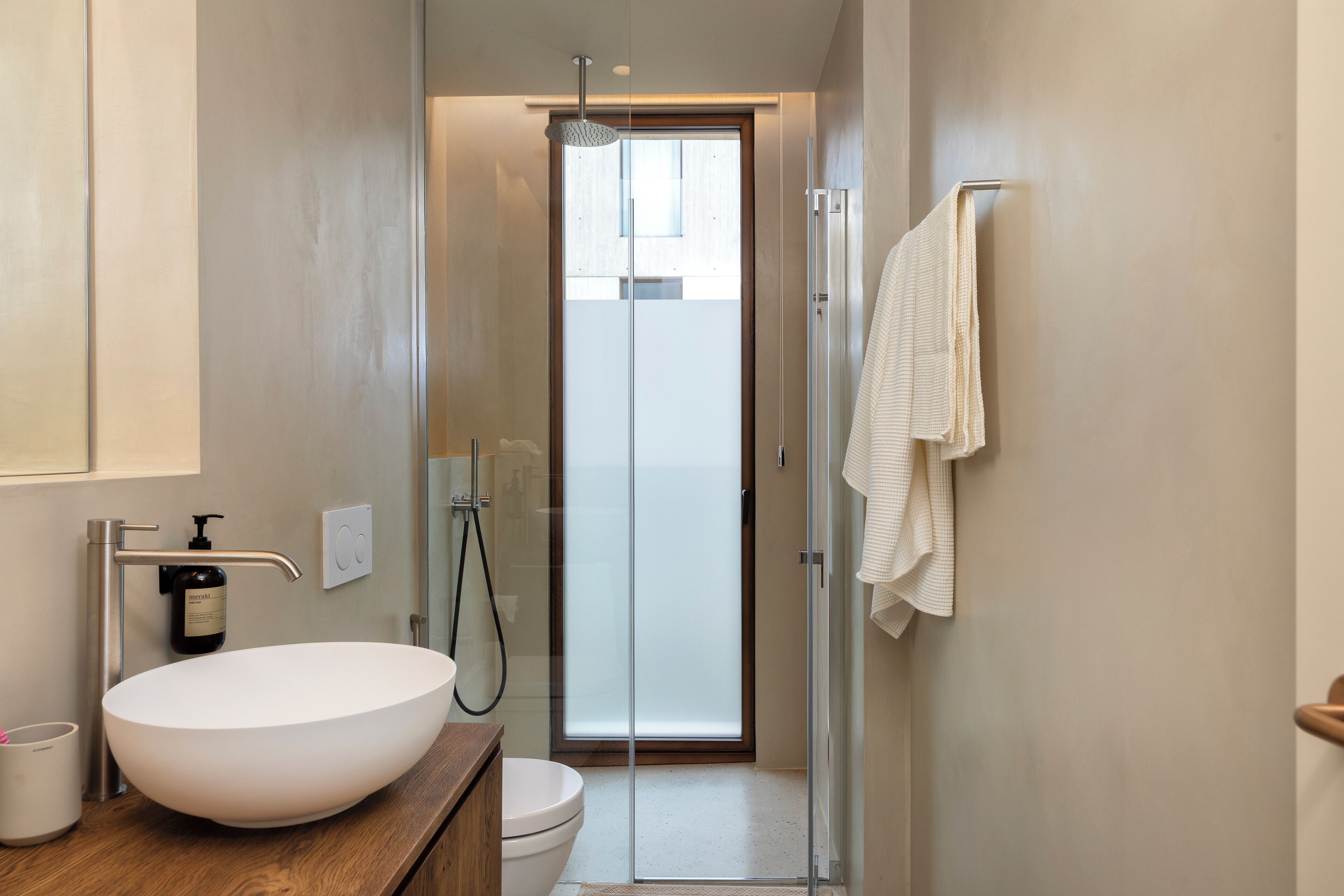 Une salle de bain moderne avec un grand lavabo blanc, une douche en verre et un meuble-lavabo en bois.