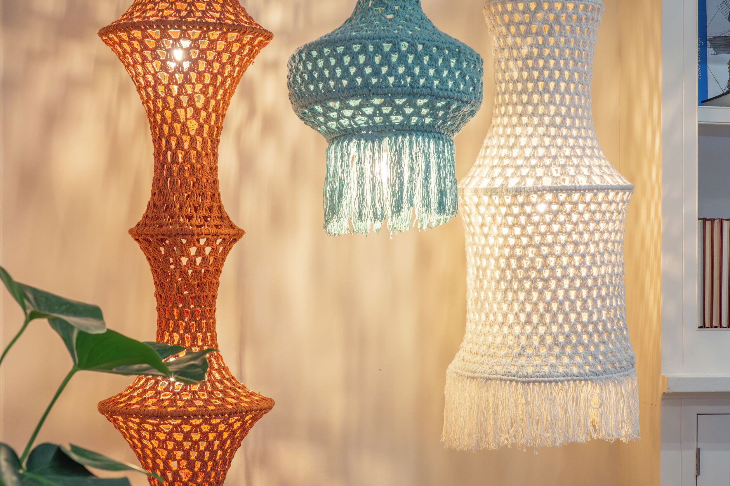 Trois lampes suspendues en crochet, ornées de glands de différentes couleurs.