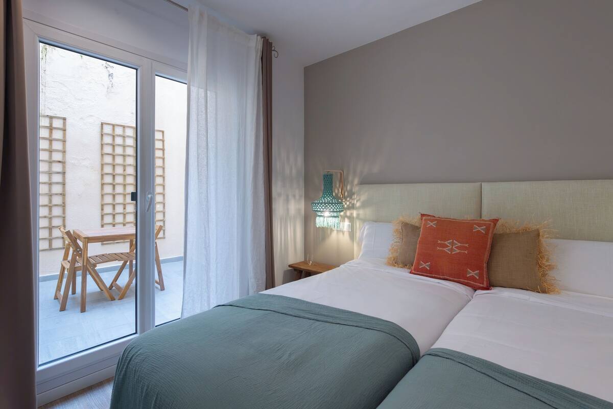 Hotelkamer met een bed, nachtkastje, tafel met stoelen en uitzicht buiten via een schuifdeur.
