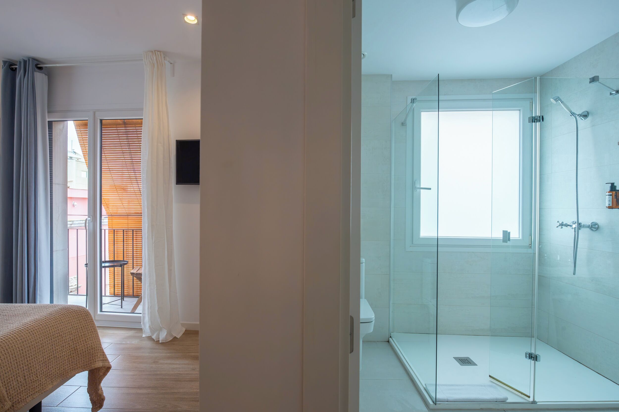 A modern bathroom with a glass-enclosed shower, a toilet, and a sink.