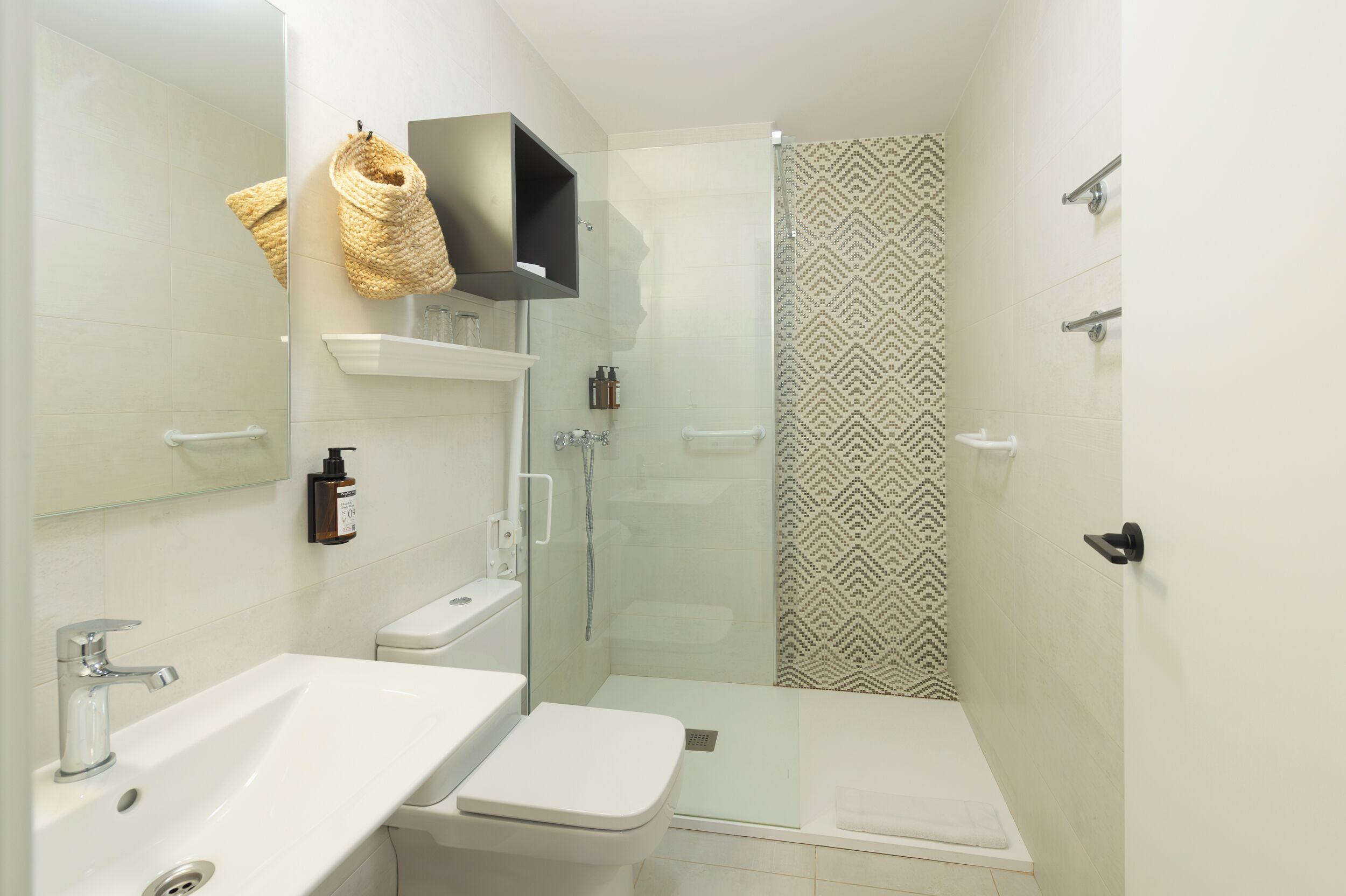 Een moderne badkamer met een douchecabine van glas, een wit wastafelmeubel en een toilet.