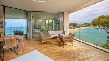 A balcony with wooden flooring, wicker furniture, and a glass door leading to a room.