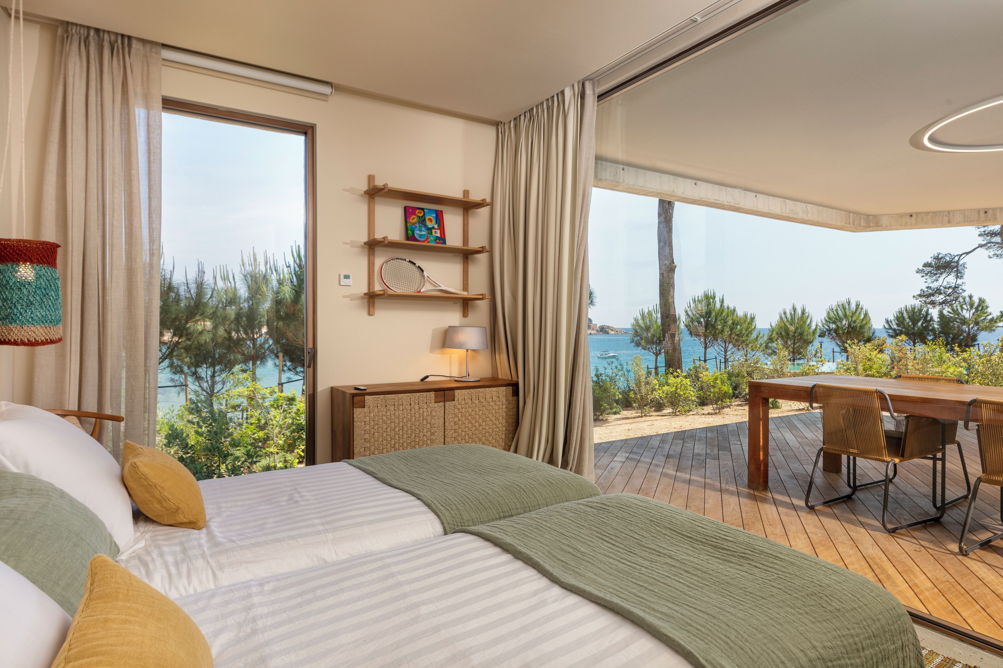 A bedroom with a large bed, a wooden desk, and a view of the sea.