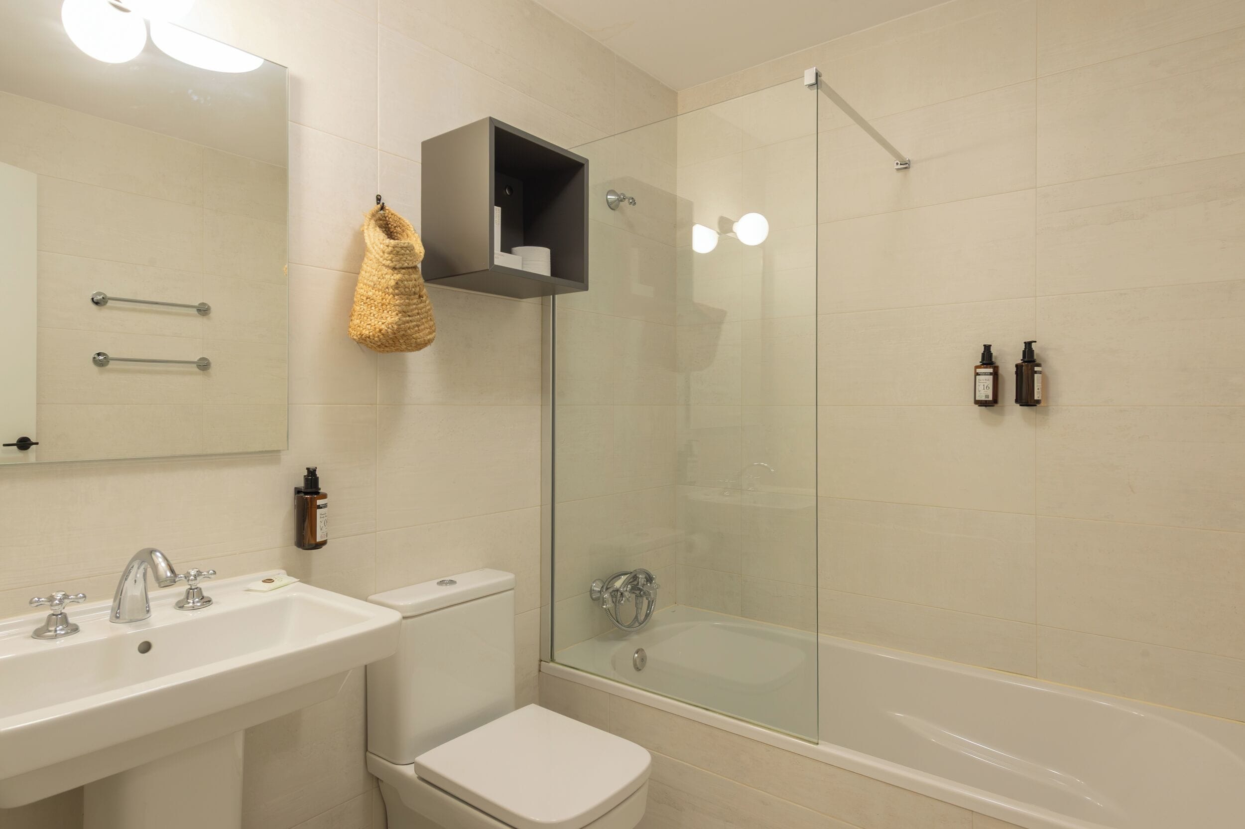 A modern bathroom with a glass-enclosed shower, a white sink, and a toilet.