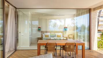 A modern room with a wooden dining table, chairs, and a glass partition.