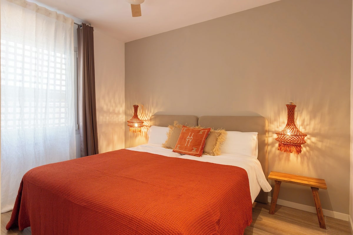 Een slaapkamer met een groot bed, twee bedlampen en een houten nachtkastje.