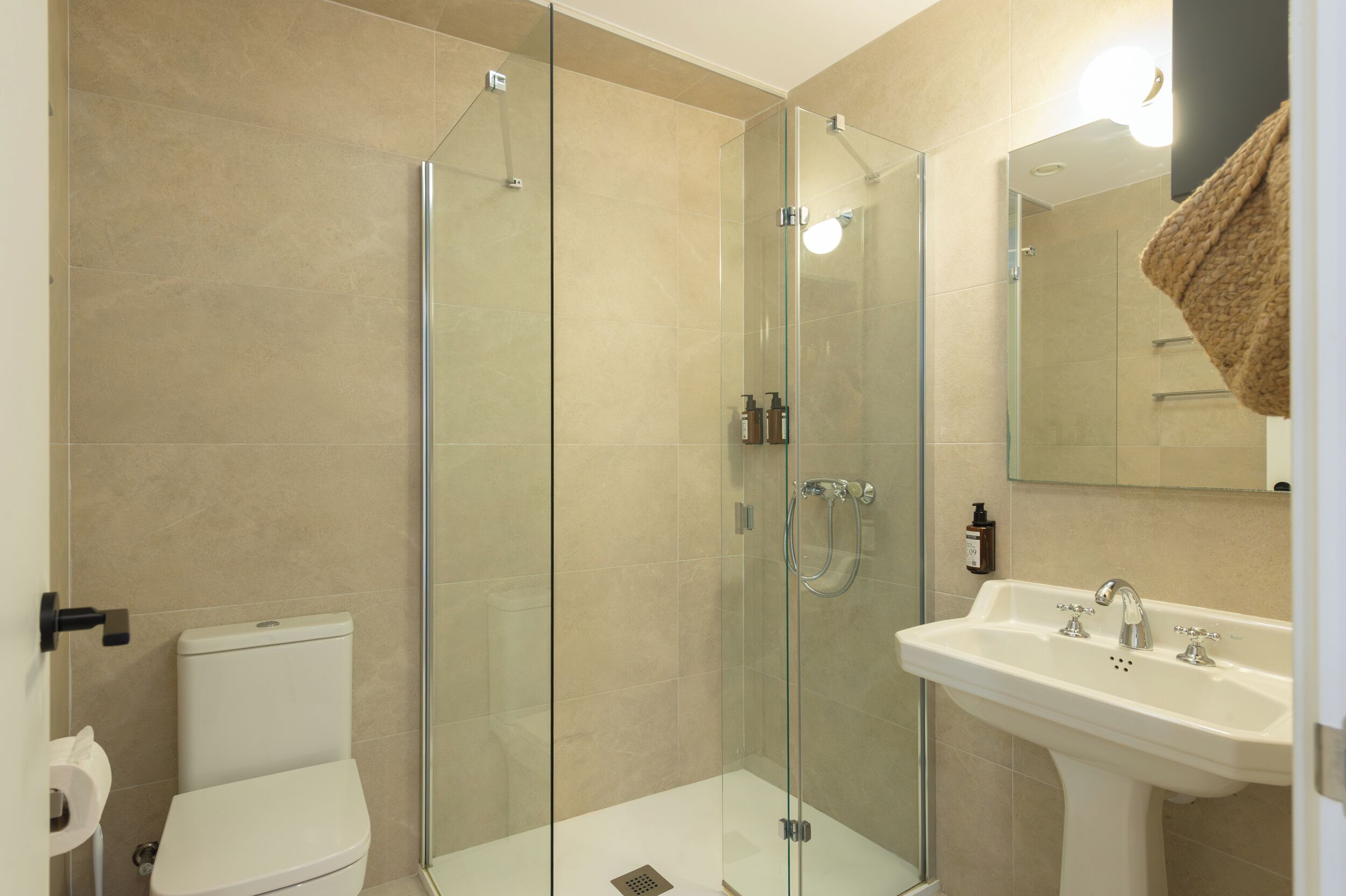 Ein modernes Badezimmer mit einer Duschkabine, einem weißen Waschbecken und einer Toilette.