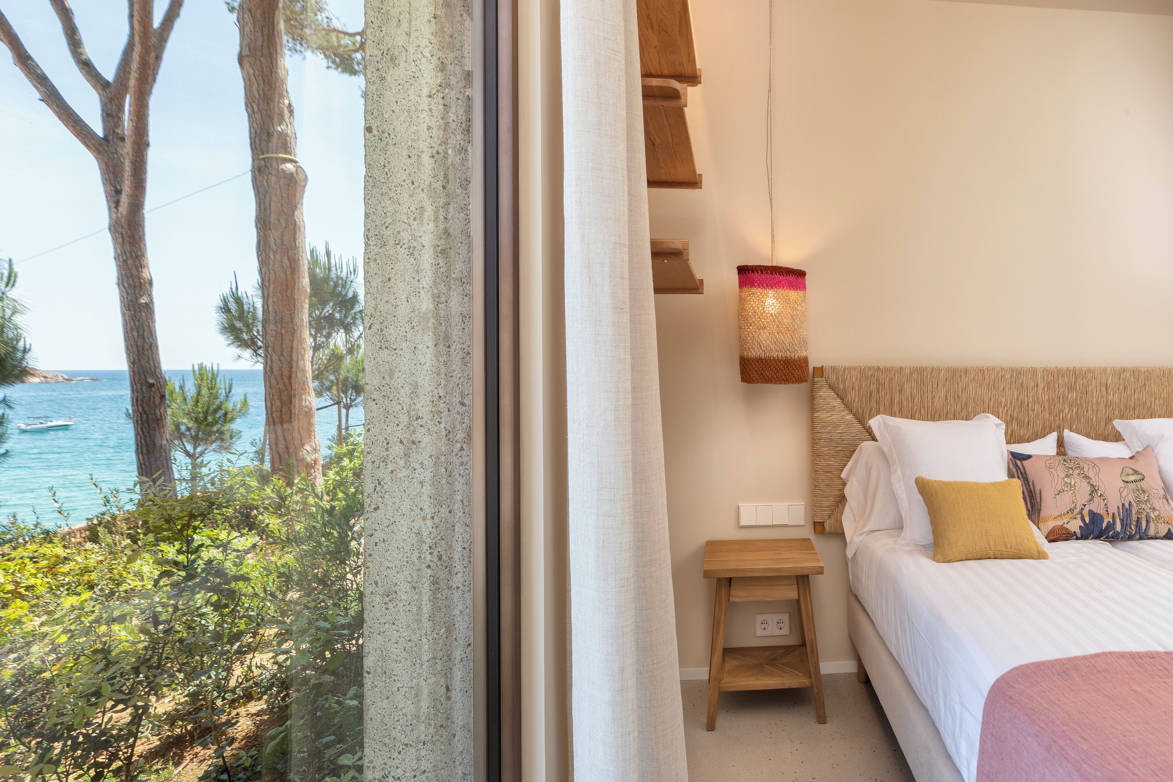 Un dormitorio con cama, mesita de noche y vista al mar.