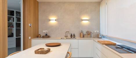 A modern kitchen with a central island, built-in appliances, and a view of the adjacent living area.