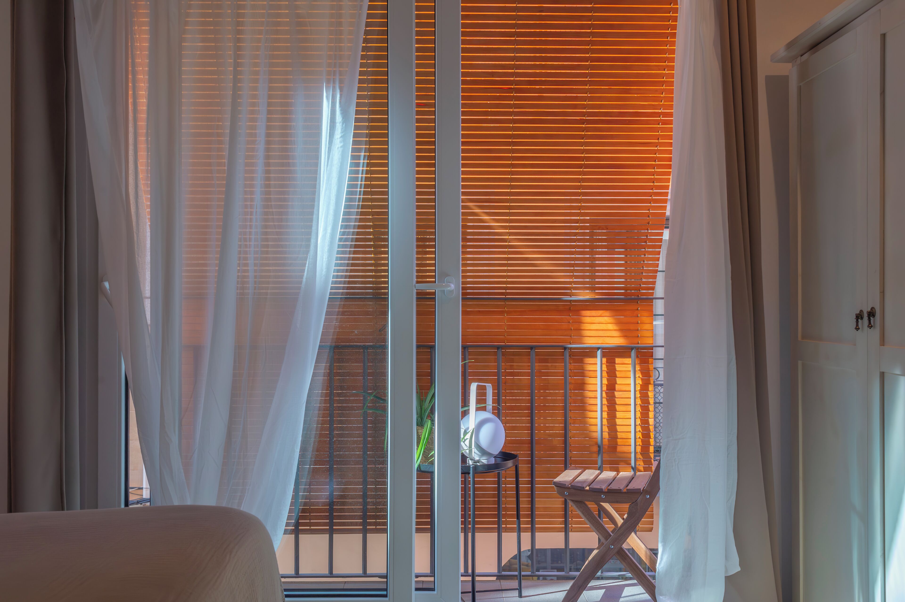 A balcony with a view of a building, a small table with a plant, and a chair.