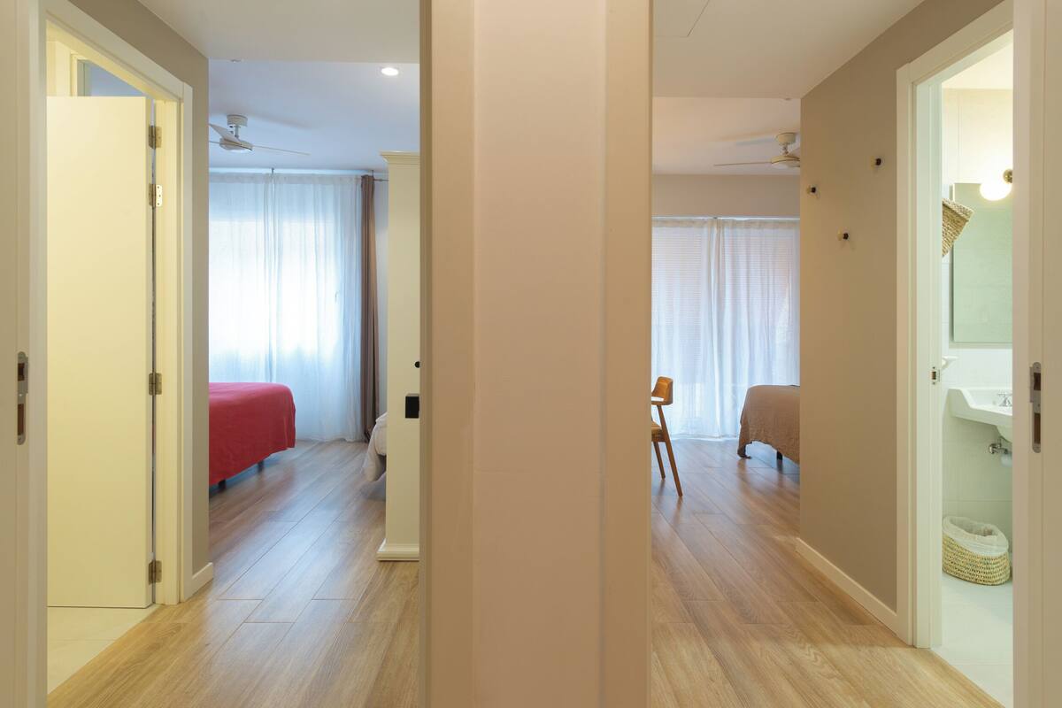 Een hotelkamer met een bed, een stoel, een nachtkastje en een badkamer met een wastafel en spiegel.