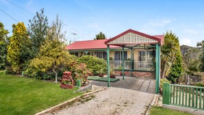 Una casa con techo rojo, un porche cubierto y un jardín bien cuidado.