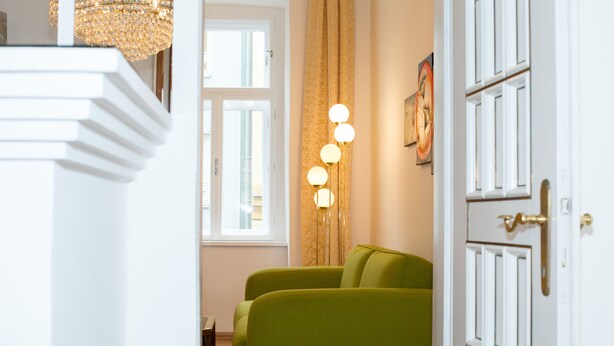 A room with a green sofa, a chandelier, and a door with a gold handle. - Marthas Veranda Apartment (Vienna)