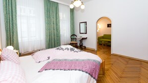A bedroom with a large bed, a chair, a small table, and a green sofa. - Marthas Veranda Apartment (Vienna)
