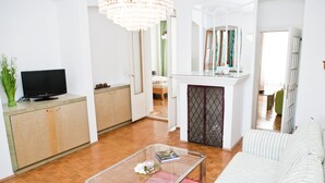 A modern living room with a glass coffee table, a sofa, a television, and a fireplace. - Marthas Veranda Apartment (Vienna)