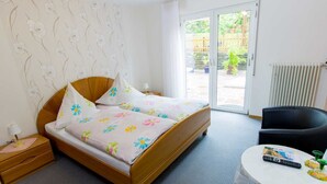 A hotel room with a bed, a bedside table, a chair, a small table with a remote control, and a view of the outside. - Hotel Weinhaus Moselblick (Burg)