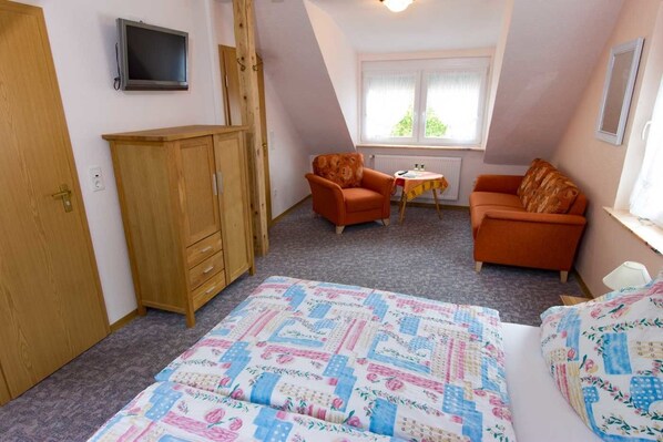 A bedroom with a bed, two orange armchairs, a wooden wardrobe, a small table, and a window with curtains. - Hotel Weinhaus Moselblick (Burg)