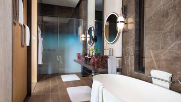 A modern bathroom with a large bathtub, a vanity with a marble countertop, and two wall-mounted mirrors.