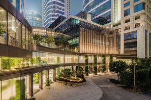 A modern hotel with a central courtyard, glass railings, and greenery.