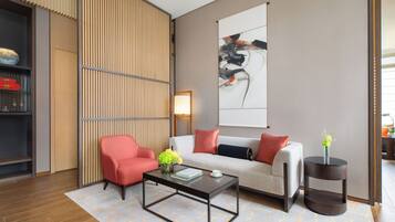 Una sala moderna con sofá, sillón, mesa de centro y un adorno en la pared.