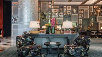 A lobby with two floral armchairs, a round table, and a decorative wall with patterned panels.