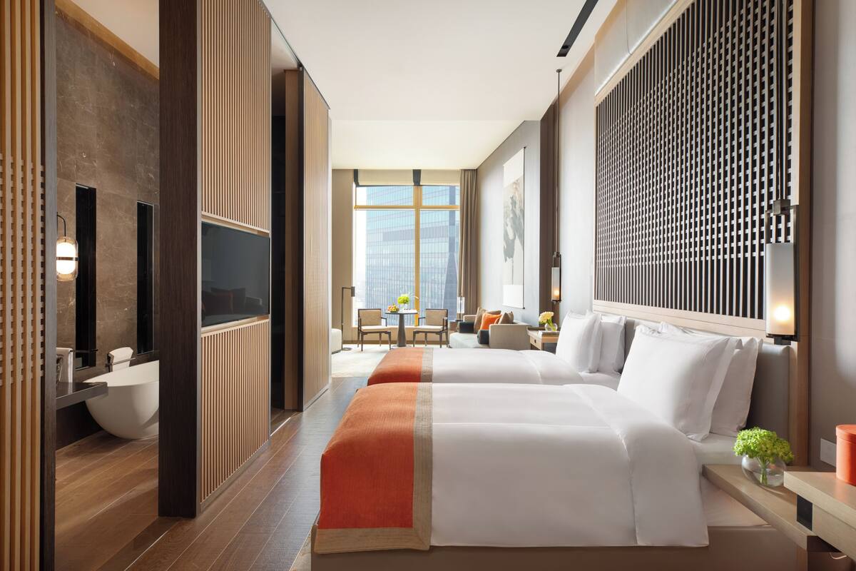Une chambre d’hôtel avec un grand lit, une télévision, une salle de bain et une vue sur la ville.