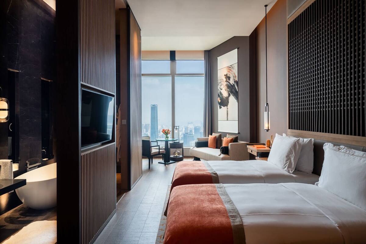 Une chambre d’hôtel avec un grand lit, une télévision, un bureau et une vue sur la ville.