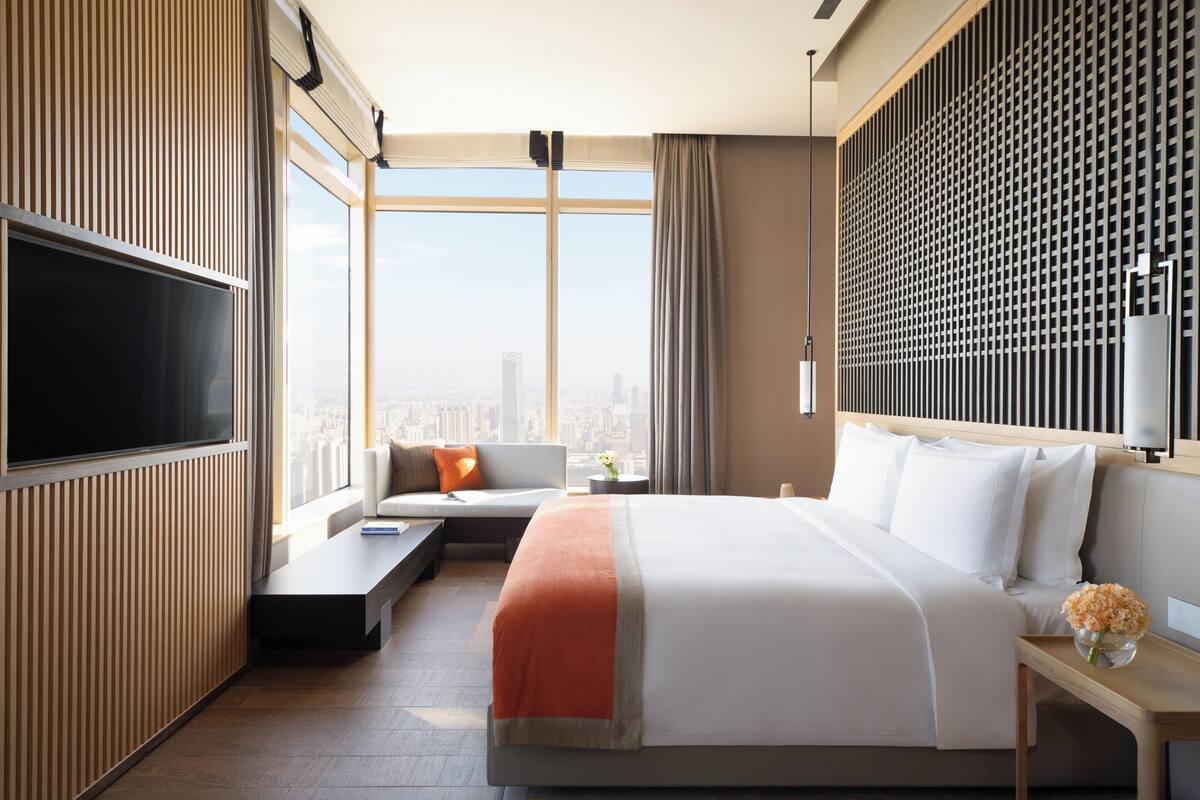 Une chambre d’hôtel dotée d’un grand lit, d’une télévision, d’un coin salon et offrant une vue sur la ville.