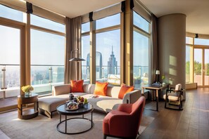 Un salon spacieux avec un grand canapé, une table basse et une vue sur les toits de la ville.